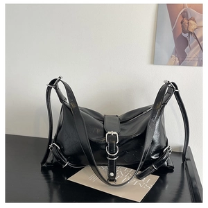 Detail of black glossy wrinkled texture underarm bag with silver buckle straps