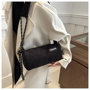 Close-up of black corduroy cylinder bag featuring FASHION label and woven rope strap