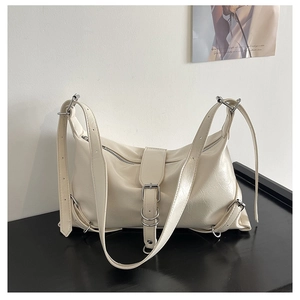 Detailed shot of cream-colored wrinkled leather texture and silver buckle accents on shoulder bag