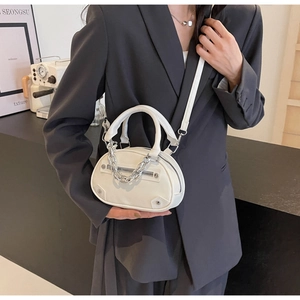 Close-up of white leather mini crossbody bag with silver chain and rivet details