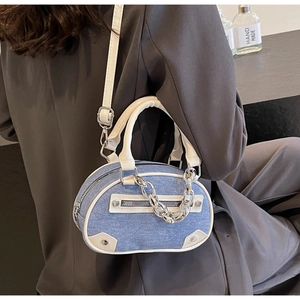 Detail of blue denim mini Boston bag with white leather trim and silver metal chain