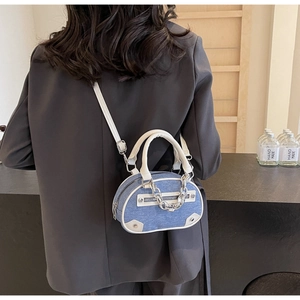 Detail of blue denim crossbody bag with white leather trim and silver chain handle