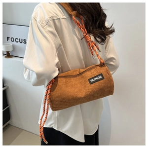 Detailed texture of brown corduroy cylinder bag with woven rope shoulder strap