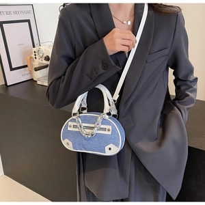 Detail of blue denim and white leather crossbody bag with silver chain on model