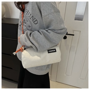 Detail of off-white corduroy barrel bag with orange braided rope strap and fashion label
