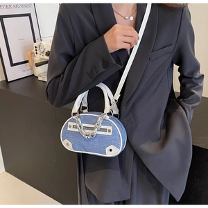 Detail of blue denim crossbody bag with silver chain and white leather strap on a model