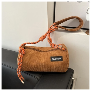 Detail view of brown corduroy cylinder bag with textured fabric and braided rope strap