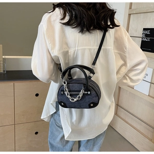Detail of dark gray denim mini oval bag with silver chain and black leather handles