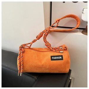 Detail of orange corduroy barrel bag with woven rope strap and FASHION label