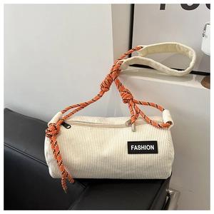 Close-up of beige corduroy cylinder bag with orange-black rope strap and fashion label