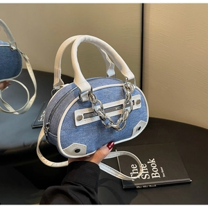 Detail of blue denim bowling bag with white leather trim and chunky silver metal chain