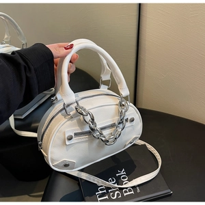 Close-up of white semi-oval handbag with silver chain decor and metal rivet details