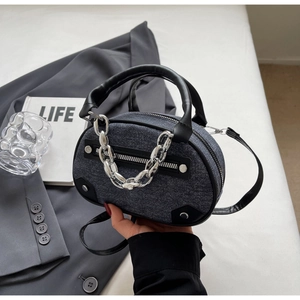 Detail of blue denim crossbody bag with silver chain decoration and leather trim