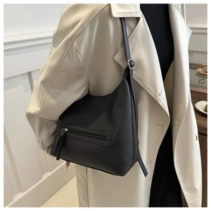 Detail of black lychee grain leather shoulder bag showing zipper and metal buckle