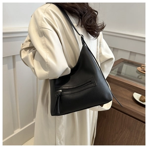 Detail of black pebbled leather texture and metal zipper with tassel on bucket bag