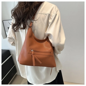 Close-up of caramel brown pebble leather texture and zipper detail on shoulder bag