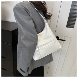 Detail of white leather shoulder bag featuring lychee grain texture and tassel zipper