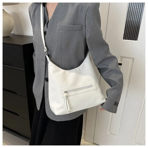 Detailed view of white hobo bag featuring pebbled texture and front zipper on model