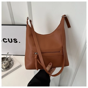 Detail of a brown lychee pattern leather shoulder bag with a front zip and knotted puller