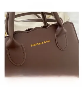 Detailed close-up of brown leather handbag featuring scallop edges and gold metal hardware