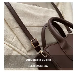 Detail of adjustable shoulder strap with gold metal buckle on dark brown leather tote bag
