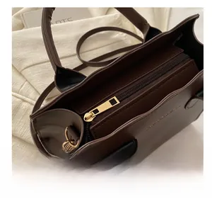 Close-up of golden metal zipper and D-ring hook on a dark brown vintage tote bag