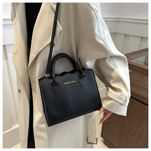 Detail of black wave edge tote bag with gold lettering and slim shoulder strap