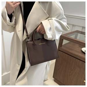Detail of coffee brown matte PU leather shoulder bag with gold hardware and logo
