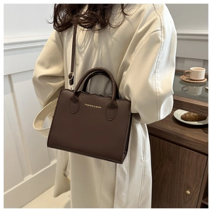 Detail of dark brown wavy edge shoulder bag shown on model with lifestyle props