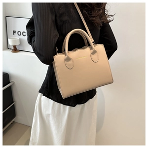 Lifestyle shot of an apricot crossbody tote bag with wavy edges and shoulder strap