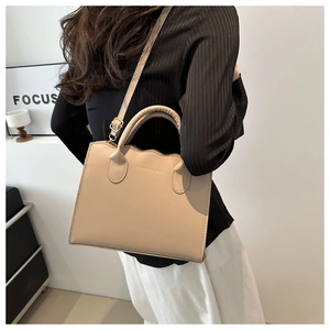 Detail of beige tote bag featuring unique wavy edge cut and adjustable shoulder strap