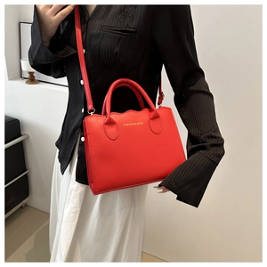 Detail of red PU leather tote with gold-embossed FASHION & BAGS logo and strap