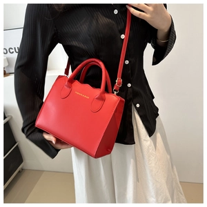 Detail of red leather crossbody bag with wavy edges and gold brand logo for women