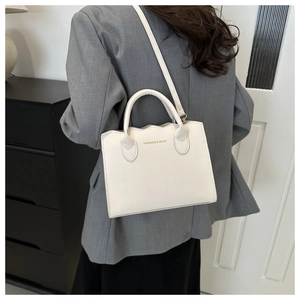 White wavy edge crossbody tote bag shown on a model in a minimalist urban fashion setting