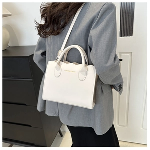 Detail of a wavy edge cream PU leather crossbody bag with fashion gold lettering