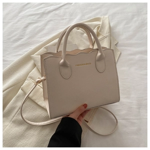 Detail of wavy top edge and gold FASHION & BAGS lettering on beige faux leather tote