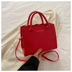 Detail of red wavy edge tote bag with top handles and adjustable shoulder strap