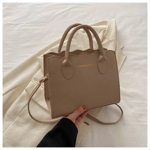 Detail of khaki wavy edge tote bag in matte PU leather with round handles and gold text