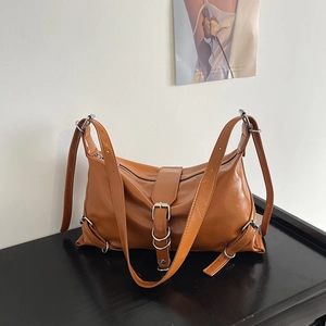 Caramel brown large hobo shoulder bag with silver hardware on black wooden surface