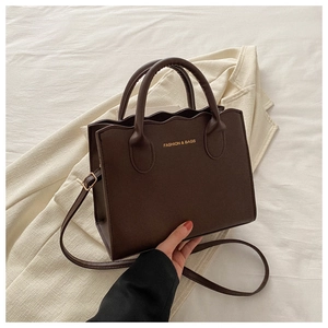 Detail of dark brown wavy edge handbag with golden Fashion & Bags logo and gold hardware