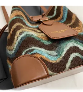 Close-up of knit wave texture and brown leather trim on a stylish bucket handbag