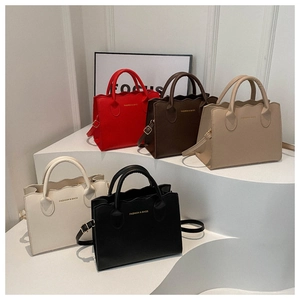 Multiple wavy-edge tote bags in red, brown, and black displayed on white platforms