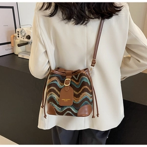 Close-up of retro wave pattern bucket bag with leather trim on model in white suit