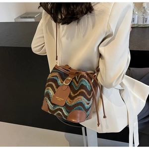 Close-up of knit bucket bag featuring wavy patterns and leather trim on a model
