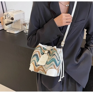 Detailed view of white bucket bag featuring colorful woven patterns and drawstring closure