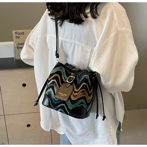 Detail of bohemian woven bucket bag featuring colorful patterns and black leather strap