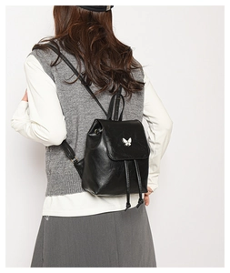Detail of vintage black PU leather backpack with silver butterfly buckle on model