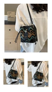 Detail of multi-color woven bucket bag with wave patterns and leather drawstring closure