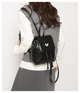 Close-up of black PU mini backpack featuring a silver butterfly buckle and drawstring detail