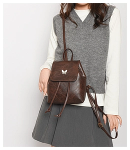 Detail of vintage dark brown mini backpack with white butterfly decor and drawstring closure
